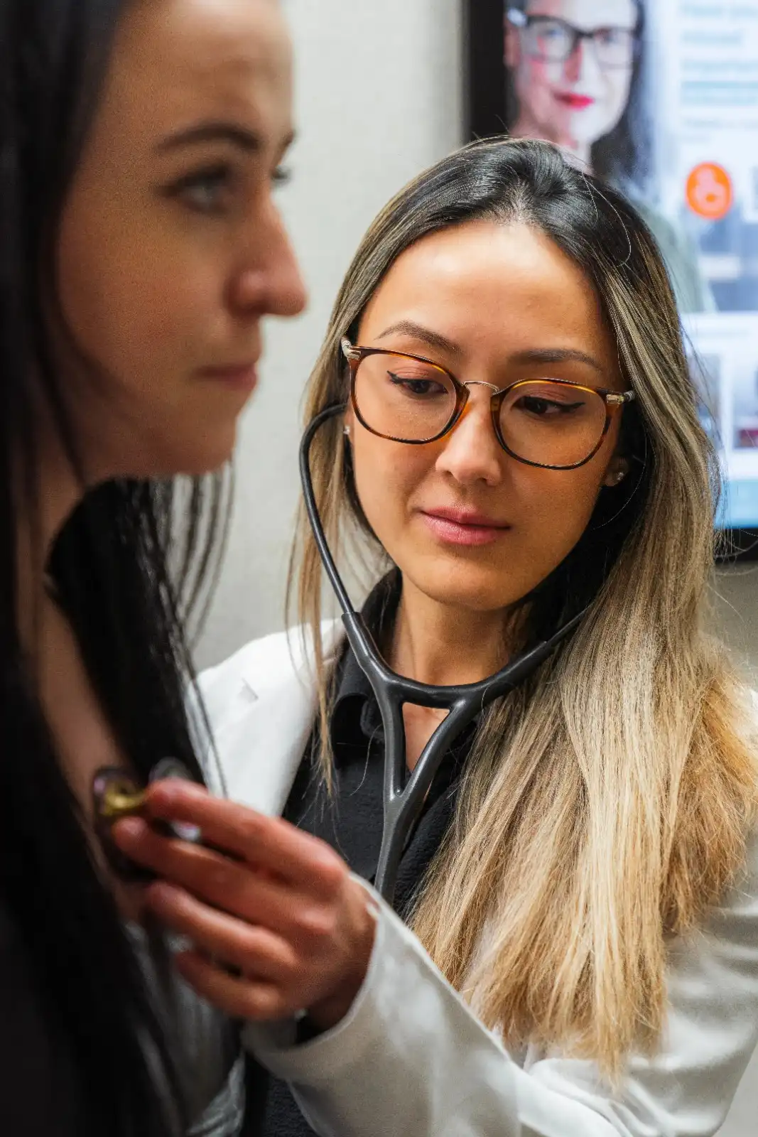 Professional portrait of Abbeygail Jiongco, FNP, in a white lab coat smiling in a clinic hallway.