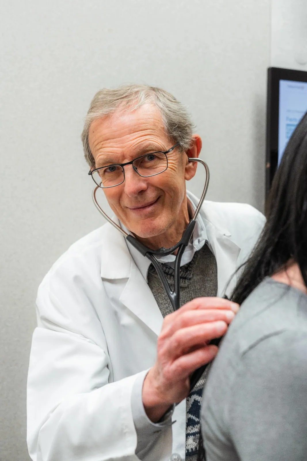 Dr. Gavrilyuk using a stethoscope to perform a heart and lung examination on a patient.