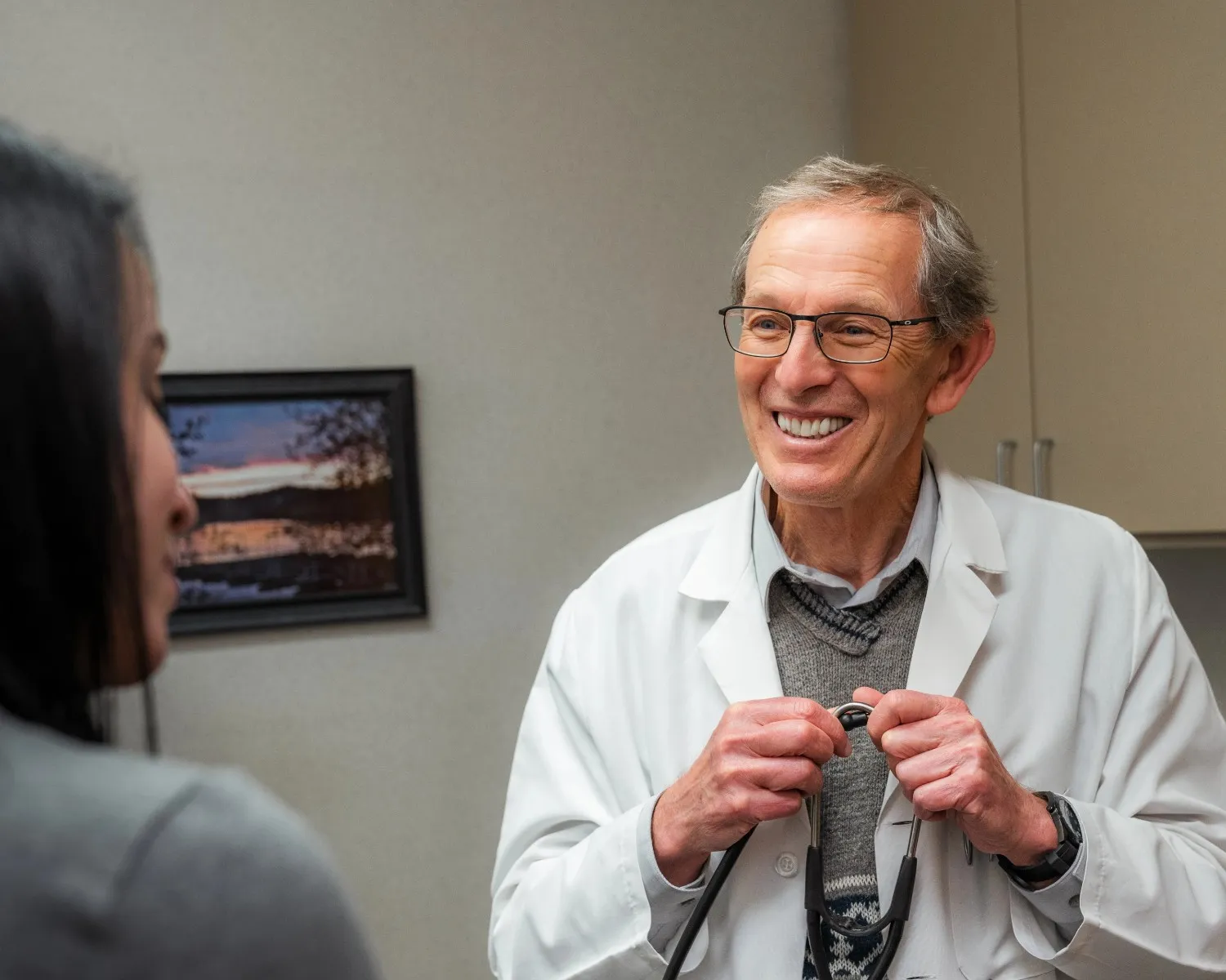 Dr. Gavrilyuk wearing a lab coat and stethoscope, looking toward the camera in a professional hallway.