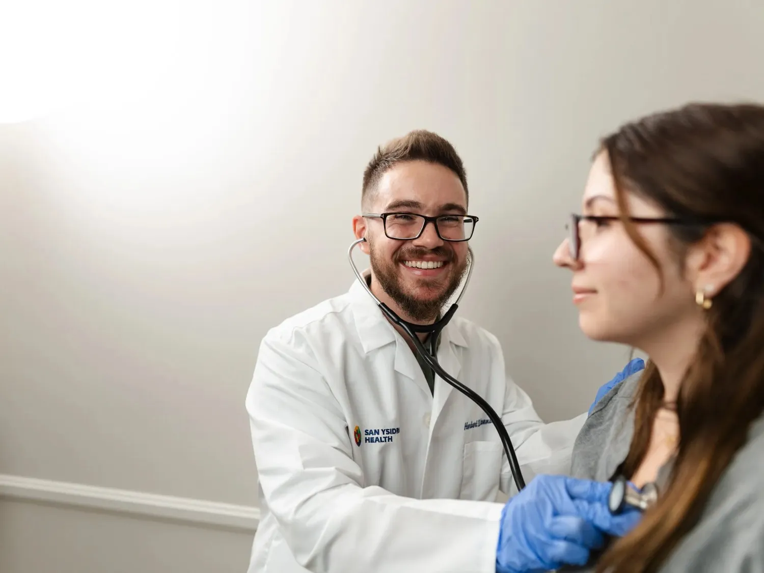Dr. Herbert Rosenbaum in a white lab coat smiling during a face-to-face discussion with a patient.