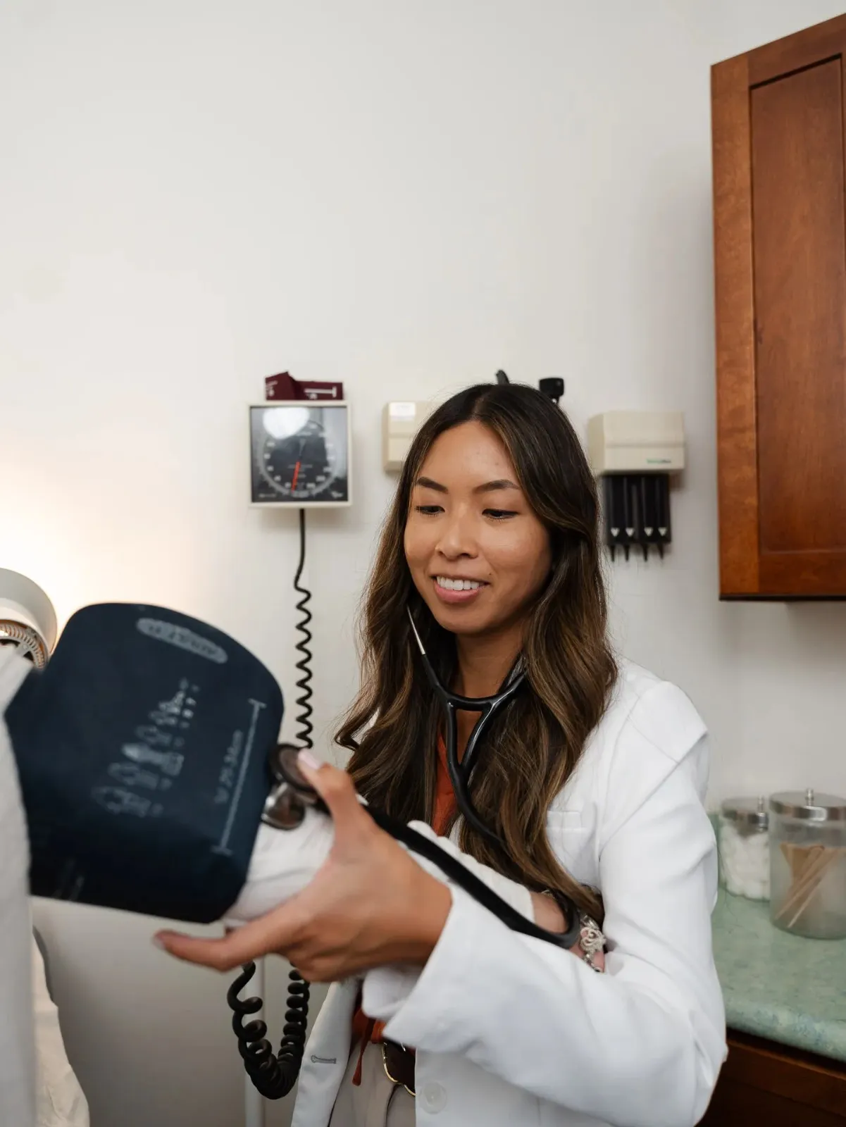 Professional portrait of Kathleen Pamilagas holding a medical device and smiling in the clinic.