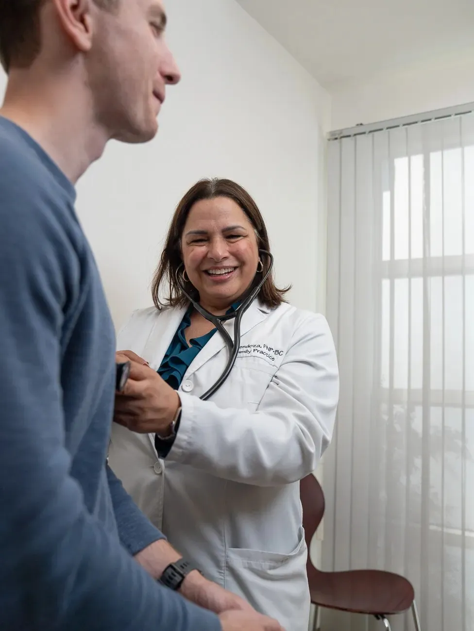 Paula Mendoza laughing warmly while providing care to a patient in the office.