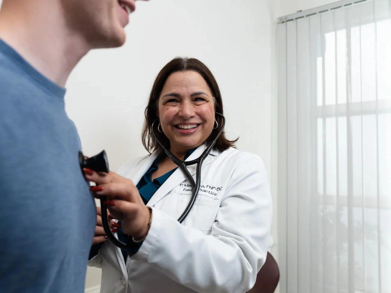 Side view of Paula Mendoza listening attentively to a patient during a consultation.