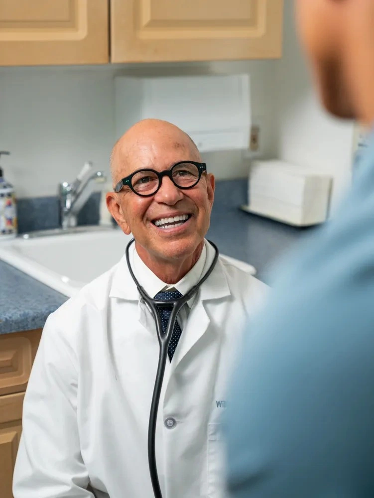 Dr. William Padilla smiling warmly while interacting with a patient during a clinic visit.