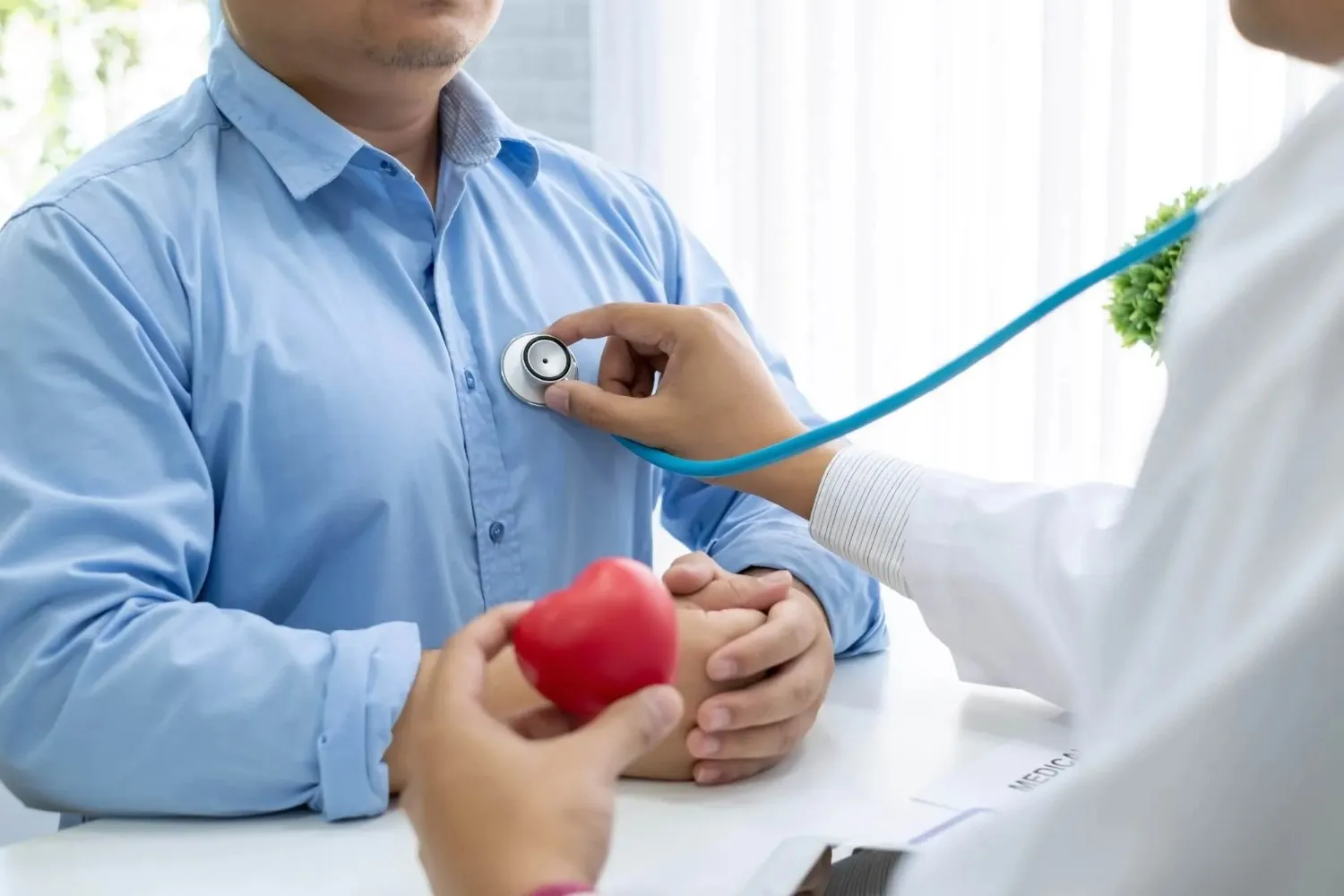 Close-up of a healthcare provider using a stethoscope to check a male patient's heart health