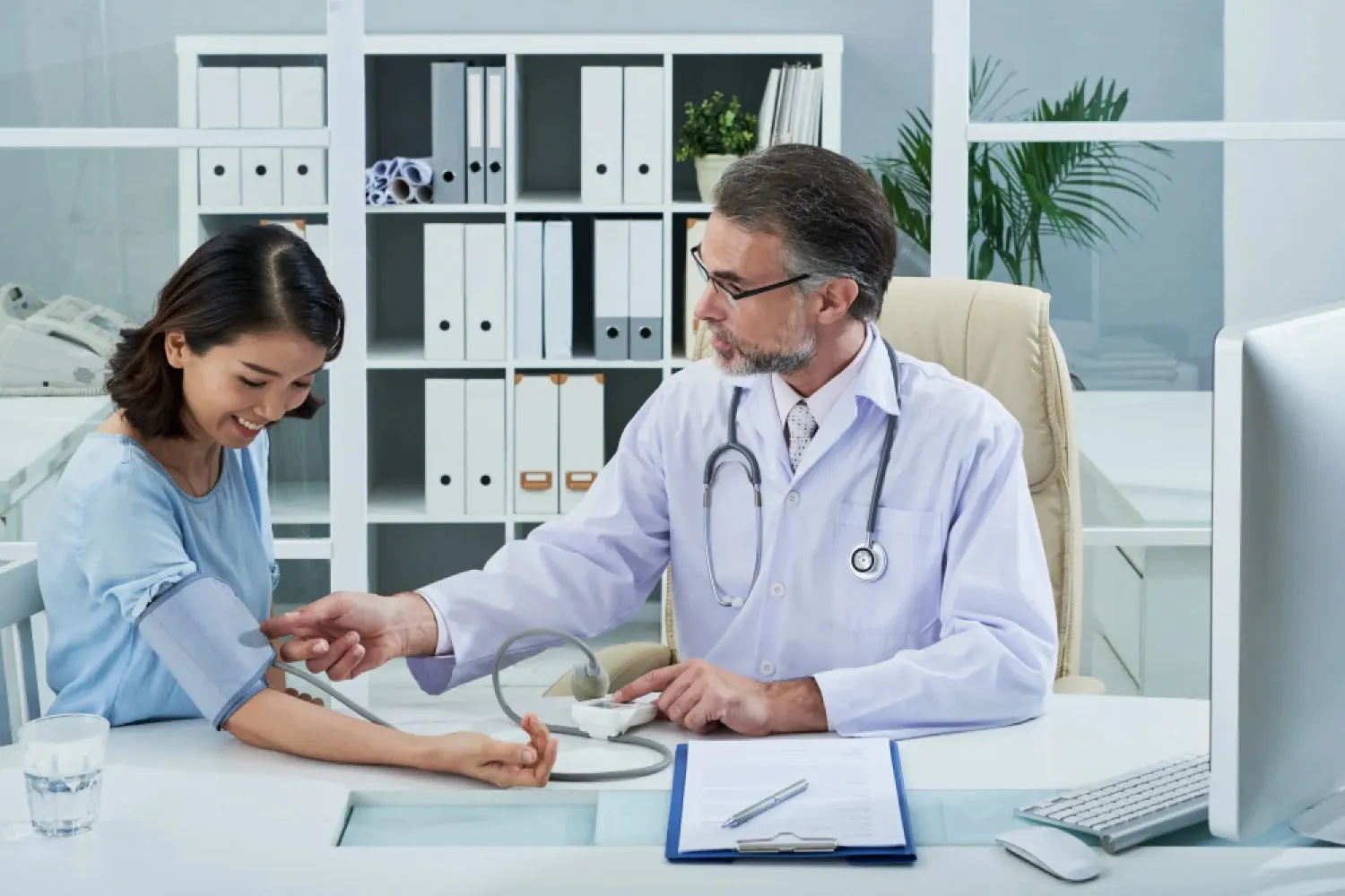 A male physician performs a routine blood pressure during a preventive care appointment